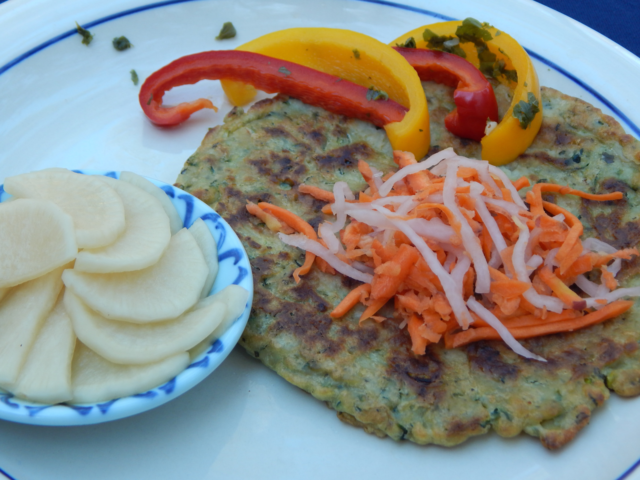 Zucchini–Basil Pancakes with, Carrot and Daikon Radish Pickles, Miso Asazuke, and pickled Bell Pepper Slices. Get the recipes at TwiceasTasty.com.